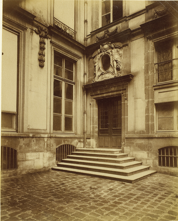 Cour intérieure. Porte surmontée d’un œil de bœuf et escalier la précédant