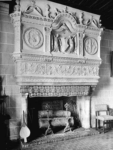 Vue intérieure de la grande salle du rez-de-chaussée : Cheminée. Deux anges portant un écusson