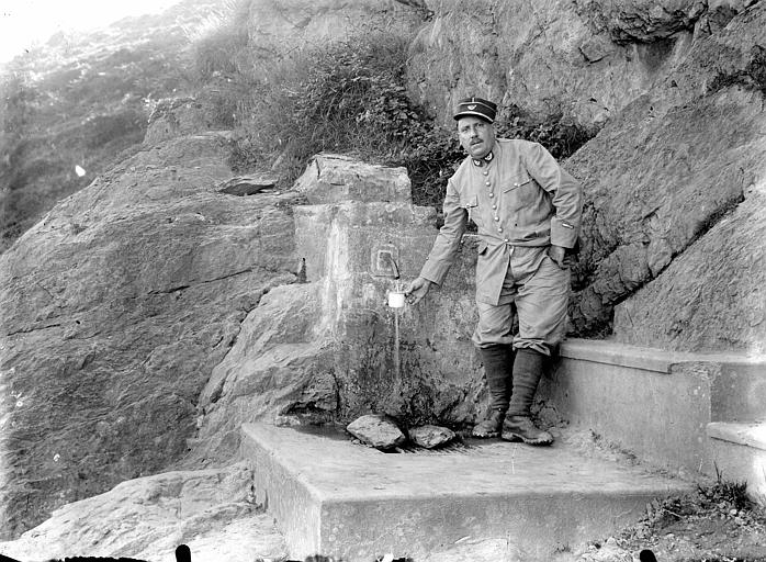 Fontaine des sources d'Ahusquy, vue rapprochée. Homme debout remplissant un verre