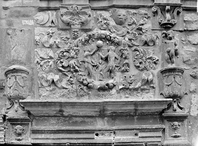 Façade sur rue : Détail d'un panneau au dessus de la petite porte, sculpté en bas-relief représentant Adam et Eve dans une couronne