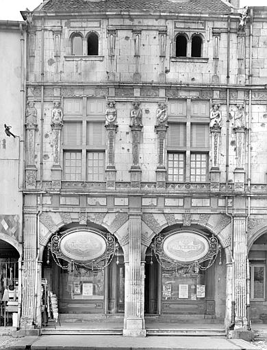 Façade à galerie d'arcades donnant sur la place, corps central de la maison. Premier étage décoré de bas-reliefs : Termes représentant les sept péchés. Commerces