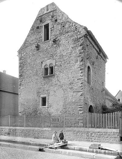 Vue de la façade à baie géminée sur rue et de la façade sur cour. Au premier plan, lavoir