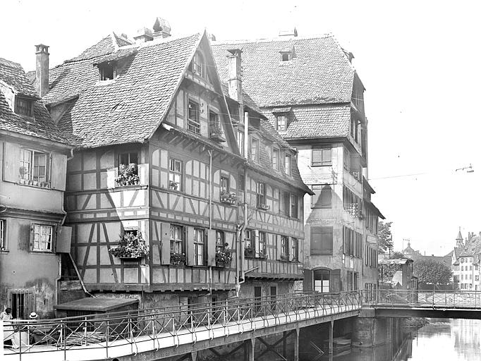 Vue d'ensemble de la rue, façades à pans de bois donnant sur l'Ill. Immeuble au second plan, après la passerelle