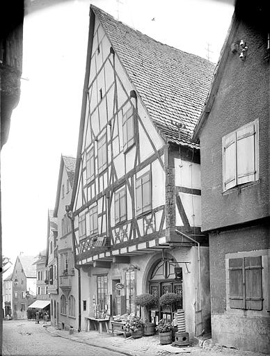 Façade sur rue à pans de bois vue de biais. Commerce. Poteau cornier orné d'un putto