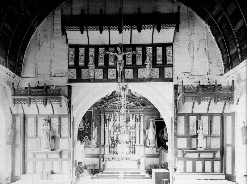 Vue intérieure de la nef côté est et du choeur : décoration de la poutre de gloire et retables des deux autels latéraux
