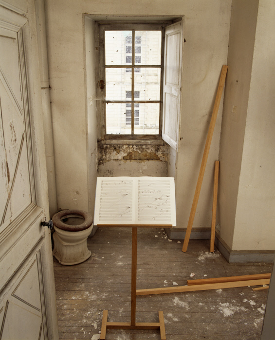 Pupitre ; partition ; mouches ; morceaux de bois ; poussière ; amplificateur ; platine cassette ; enceinte : Concerto pour mouches