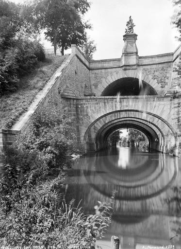 Vue prise de la berge : arches, fontaine