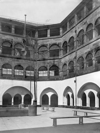 Cour intérieure : fenêtres à barreaux et galerie à arcades