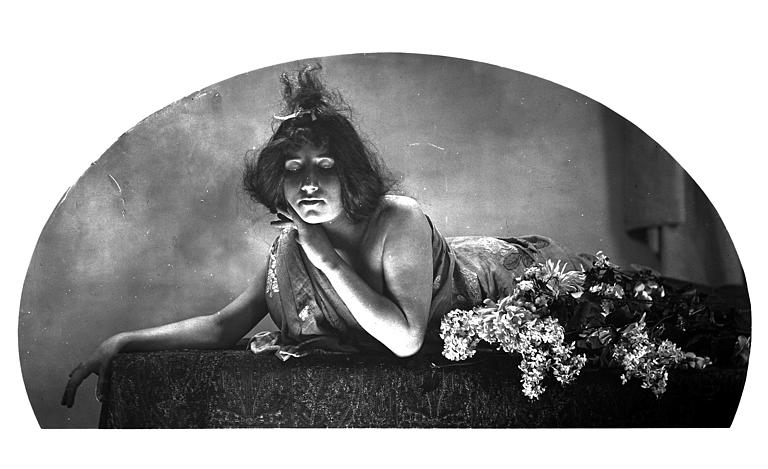 Mise en scène d'un modèle féminin : jeune femme allongée, avec un effet de lumière sur son visage