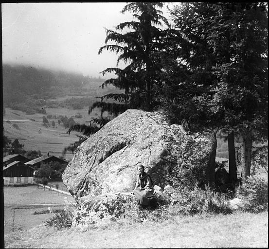 Jeune femme dans un paysage de sapins et rochers