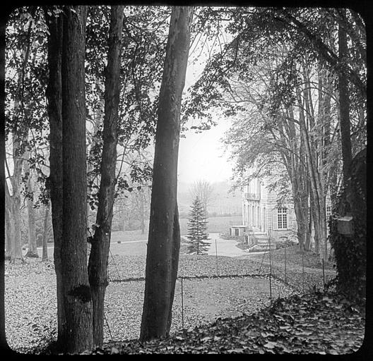 Vue partielle de la façade prise à travers un rideau d'arbres