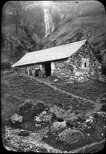 Paysanne sur le seuil de sa cabane de pierres en contrebas de la cascade du Serpent