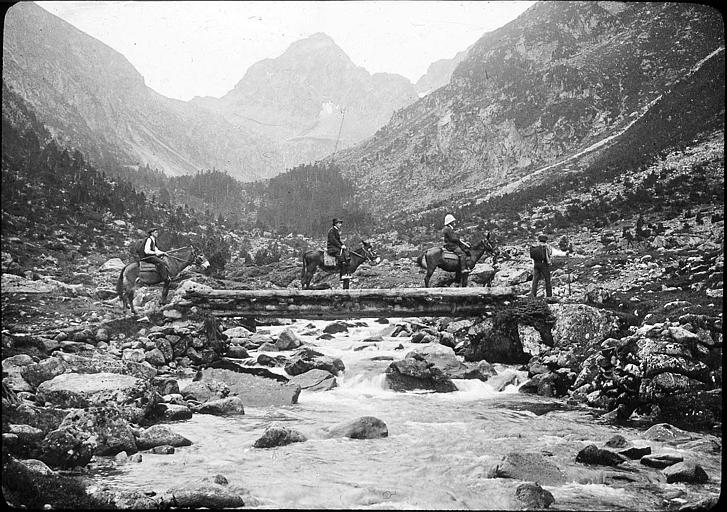 Vallée de Lutour : cavaliers passant le torrent sur un pont de bois