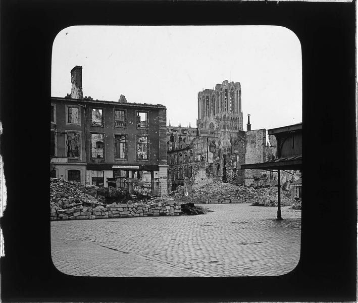 Maisons en ruines bordant la place et tours de la cathédrale en arrière-plan, côté nord