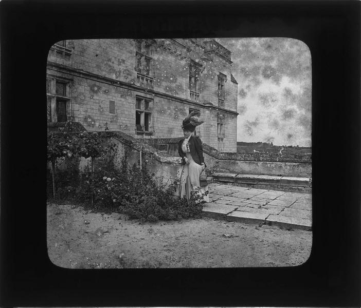 Logis royal, vue partielle de la façade est avec femme appuyée contre la rampe d'escalier donnant sur la terrasse