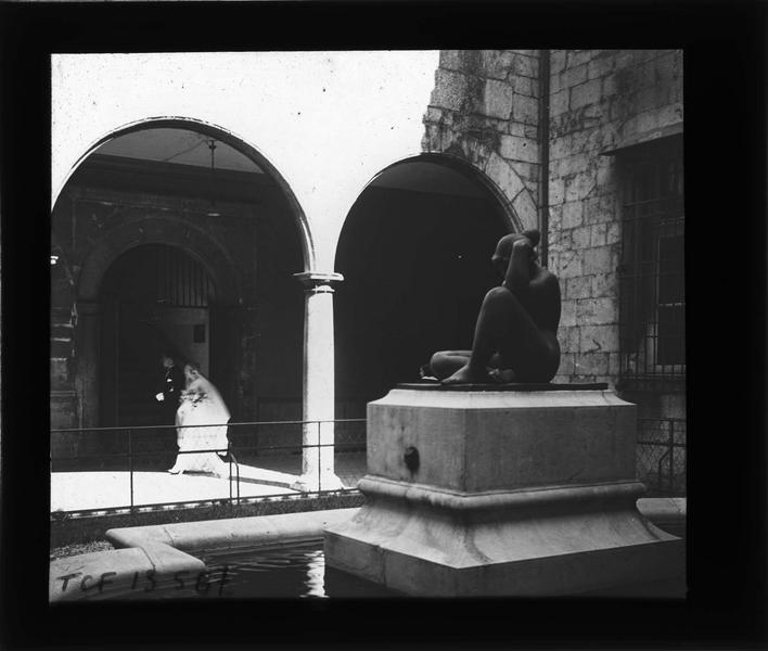 Cour intérieure avec statue de 'La Pensée' d'Aristide Maillot et mariée passant sous les arcades en arrière-plan