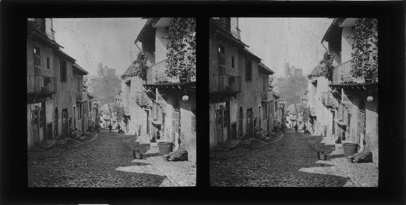 Façades sur rue animée et château en arrière-plan