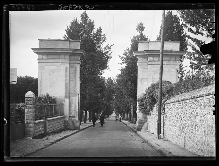 Vue rapprochée des deux pilastres formant la porte, avec perspective sur la rue