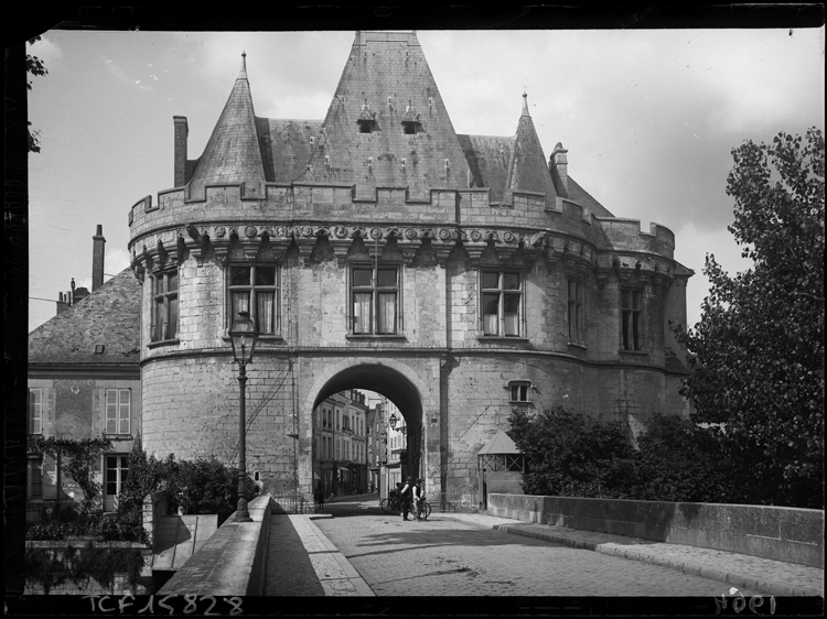 Façade extra-muros prise depuis le pont, deux cyclistes passant devant une guérite de garde