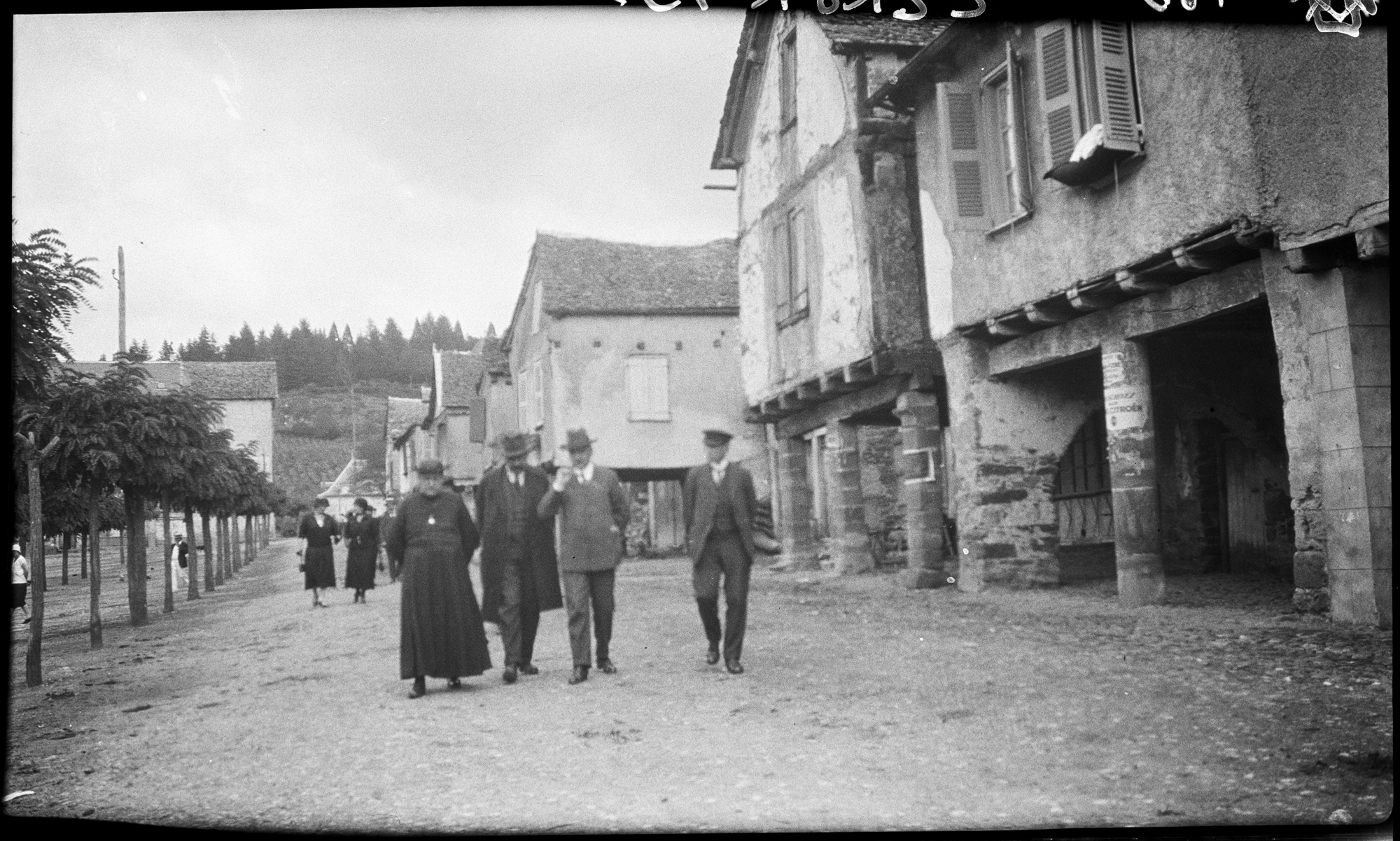Promeneurs longeant les maisons sur piliers de la place du Faubourg