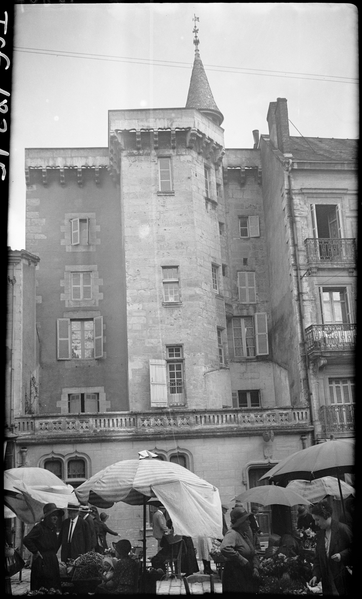 Promeneurs attablés sous des parasols, place Saint-Louis, l’arrière de la maison Tenant en arrière-plan