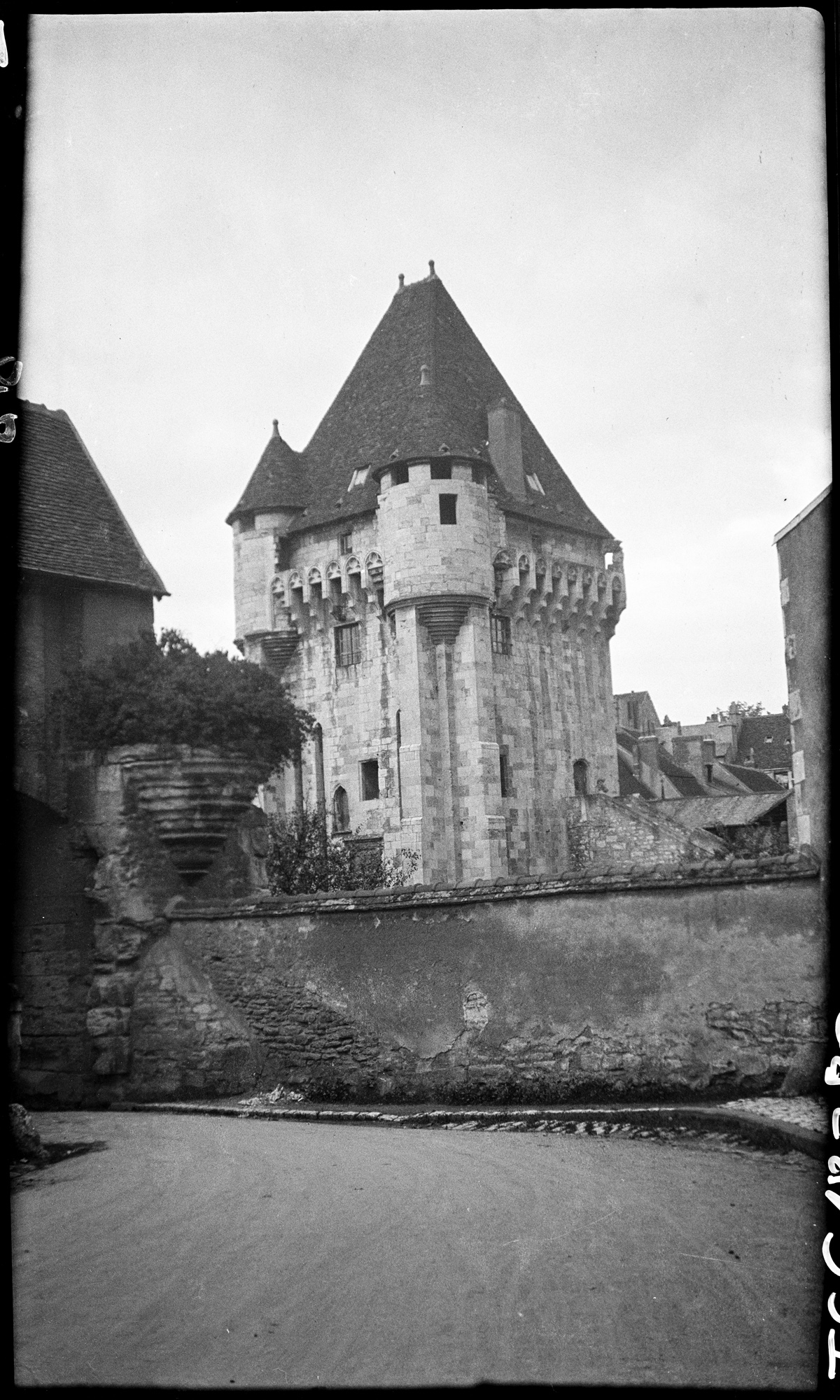 Vue d’ensemble sur la porte (1398), prise depuis son avant-porte (1422), une ruine de cul-de-lampe au premier plan