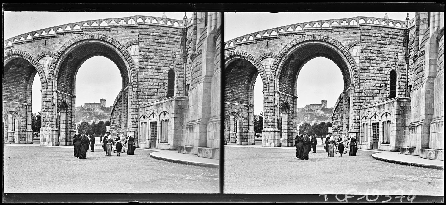 Passants sous les arcades du pont menant à la basilique de l’Immaculée-Conception