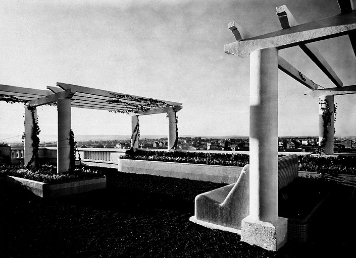 Vue du toit aménagé avec des pergolas et des bancs en mosaïque. On retrouve l'équivalent dans le jardin de la maison du directeur.