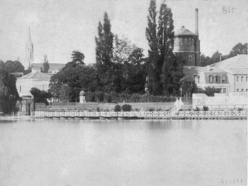Vue de l'établissement thermal depuis le lac : à droite, la tour du réservoir, le jardin et à gauche une partie de l'établissement.