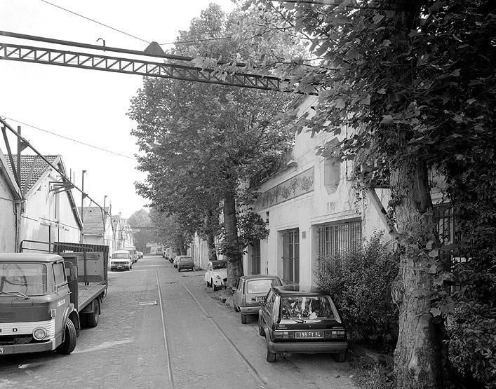 Rue intérieure avec des entrepôts à gauche et des bureaux à droite.