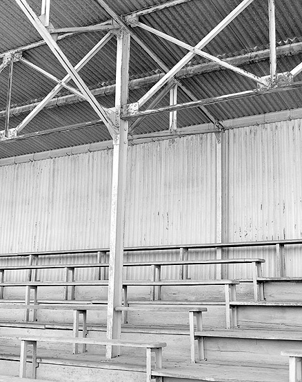 Détail des gradins en bois et de la charpente métallique des tribunes.