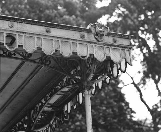 Détail du auvent de la façade ouest : lambrequins garnis de verre et gargouille en forme de tête de chien.