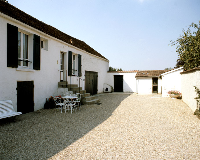 Vue de la cour avec, à gauche, le nouveau logis installé dans une partie du bâtiment agricole et, au fond, la porte d'accès au jardin de maraîcher.