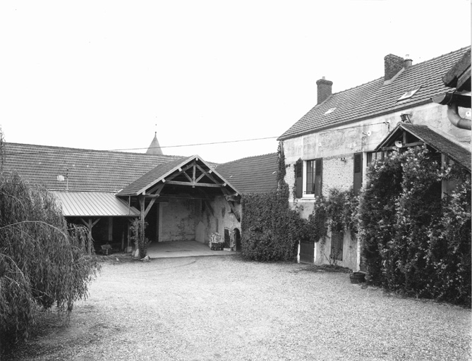 Vue de la cour de la ferme, du logis à droite, de la bergerie située dans le prolongement et de la grange au fond.