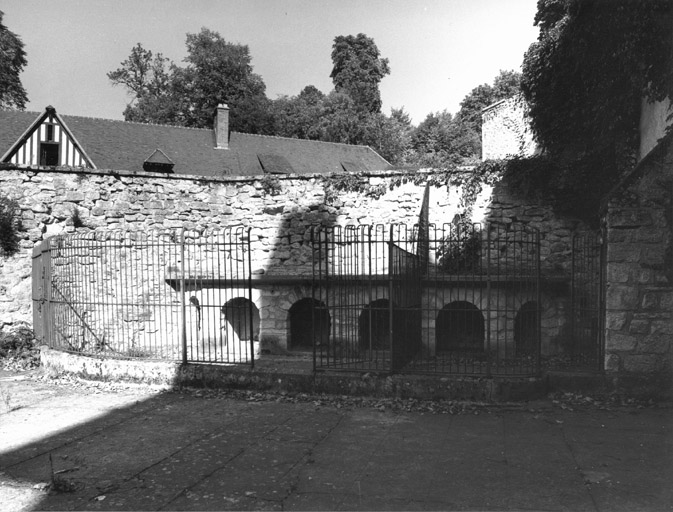 Vue de la cour des communs du château où un chenil a été installé, bordée du mur de soutènement de la cour de la ferme.