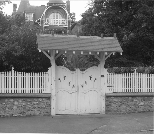 Vue d'ensemble du portail en bois protégé par un auvent de tuiles.