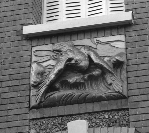 Détail d'un bas-relief en céramique situé entre deux baies.