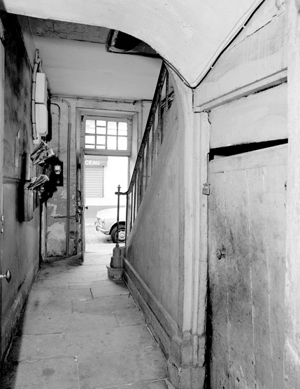 Vue d'une allée permettant de passer de la rue à la cour et aux autres corps de bâtiment. L'accès à la cave se fait sous l'escalier.