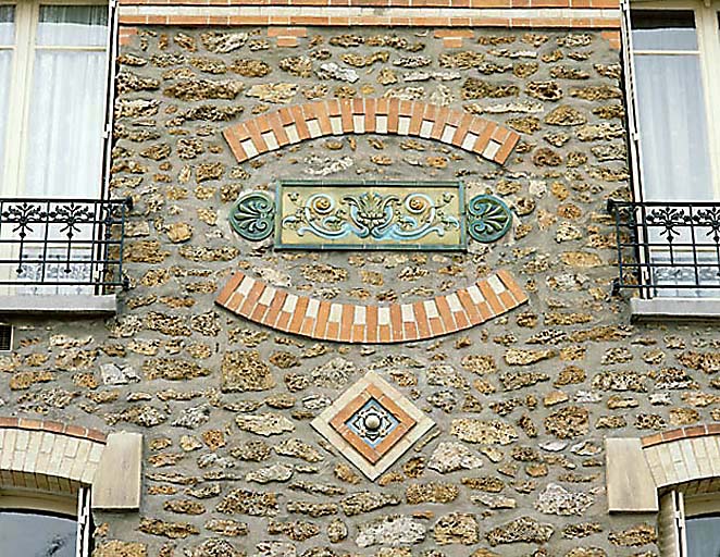 Composition décorative en céramique et brique émaillée. Le cabochon posé sur la pointe correspond au n° 36 du catalogue de vente de la manufacture Hte Boulanger et Cie datant de 1898.