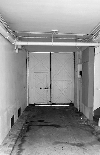 Vue de la porte cochère de l'immeuble sur rue et du départ d'escalier.