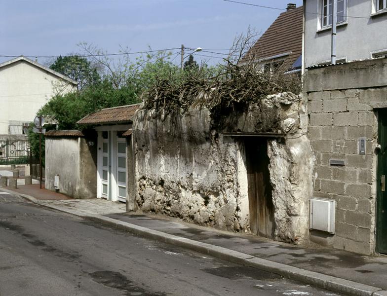 Vue générale d'un mur avec sa porte, le long de la rue.