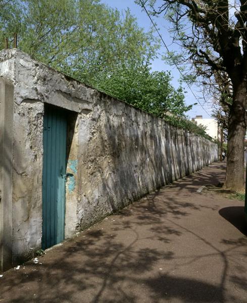 Vue générale d'un mur avec sa porte, le long de la rue.