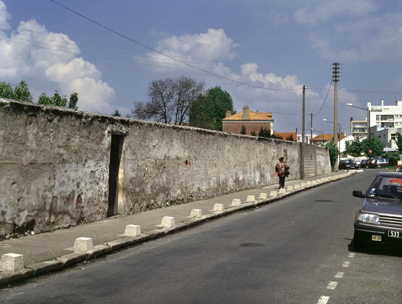 Vue générale d'un mur avec sa porte, le long de la rue.