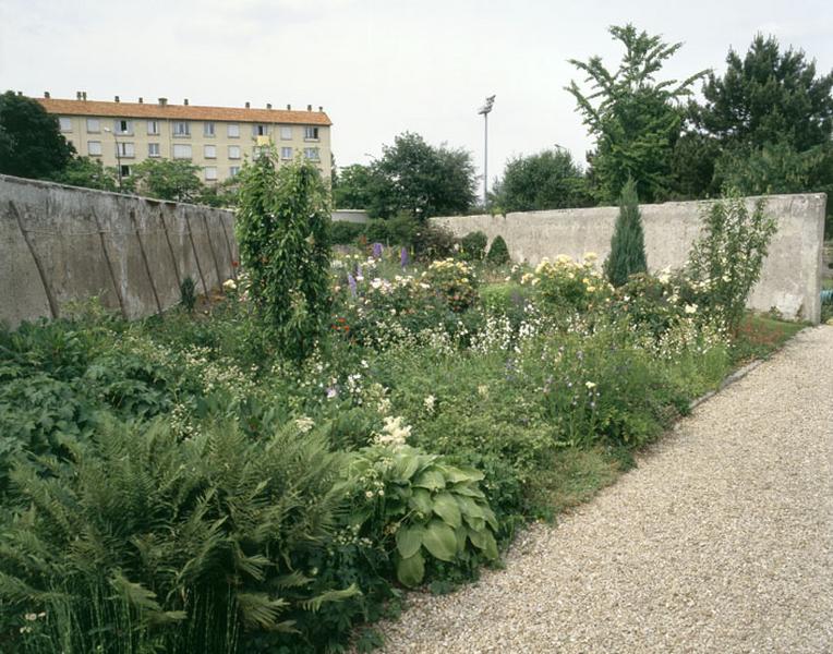 Les murs restaurés et cultures florales dans un clos réaménagé par le lycée d'horticulture.