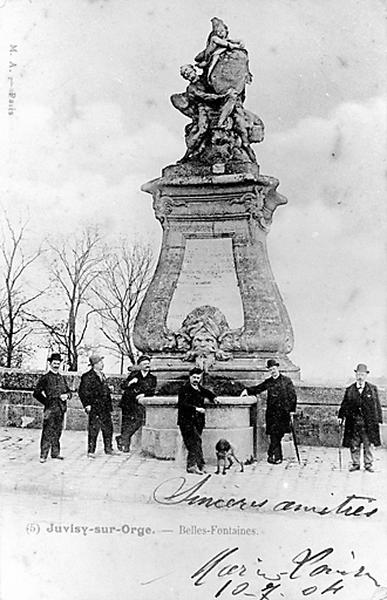 Vue de l'une des deux bornes-fontaines, encore en activité, avec socle et groupe sculpté.