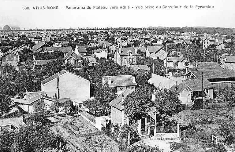 Panorama du plateau d'Athis, depuis le carrefour de la Pyramide ; à l'arrière plan, les hangars à dirigeables construits en 1921 par l'ingénieur Freyssinet et détruits par l'aviation alliée en mai 1944.