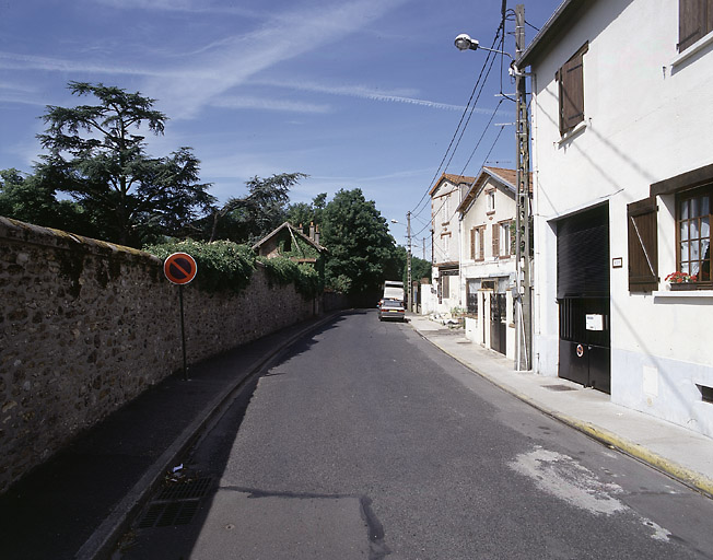 Parc d'agrément de l'ancienne clinique des Charmilles : le pavillon d'entrée et les arbres (cèdres, marronniers) qui émergent derrière l'enceinte en meulière.