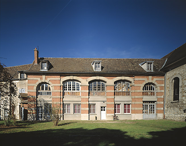 Ancien bâtiment du prieuré transformé en orangerie pour le château d'Athis. Sa façade brique et pierre date du début du 20e siècle.