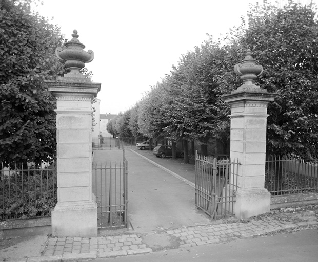 Vue de l'entrée monumentale sur la rue Samuel-Desborde, ouvrant sur l'allée des Tilleuls. Les pots décoratifs qui somment les deux piliers datent des aménagements apportés par Alphonse de Courcel. deux piliers identiques existent face à l'entrée du château.