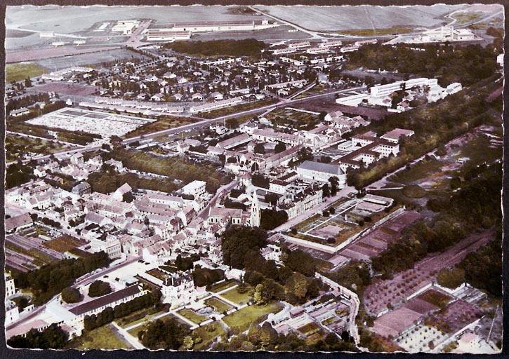 Vue aérienne : le quartier de la mairie, le vieux village et l'ancienne ferme seigneuriale, l'église, le lycée Saint-Charles. Années 1960.